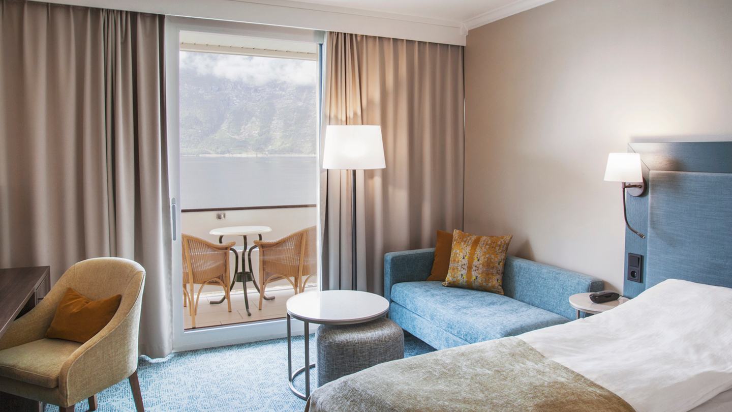 A room with a sofa, balcony and views over the Hardangerfjord