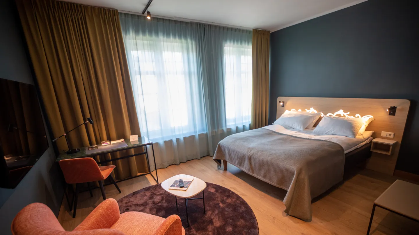 A bed and two chairs on one of the rooms at Hotel Bondeheimen