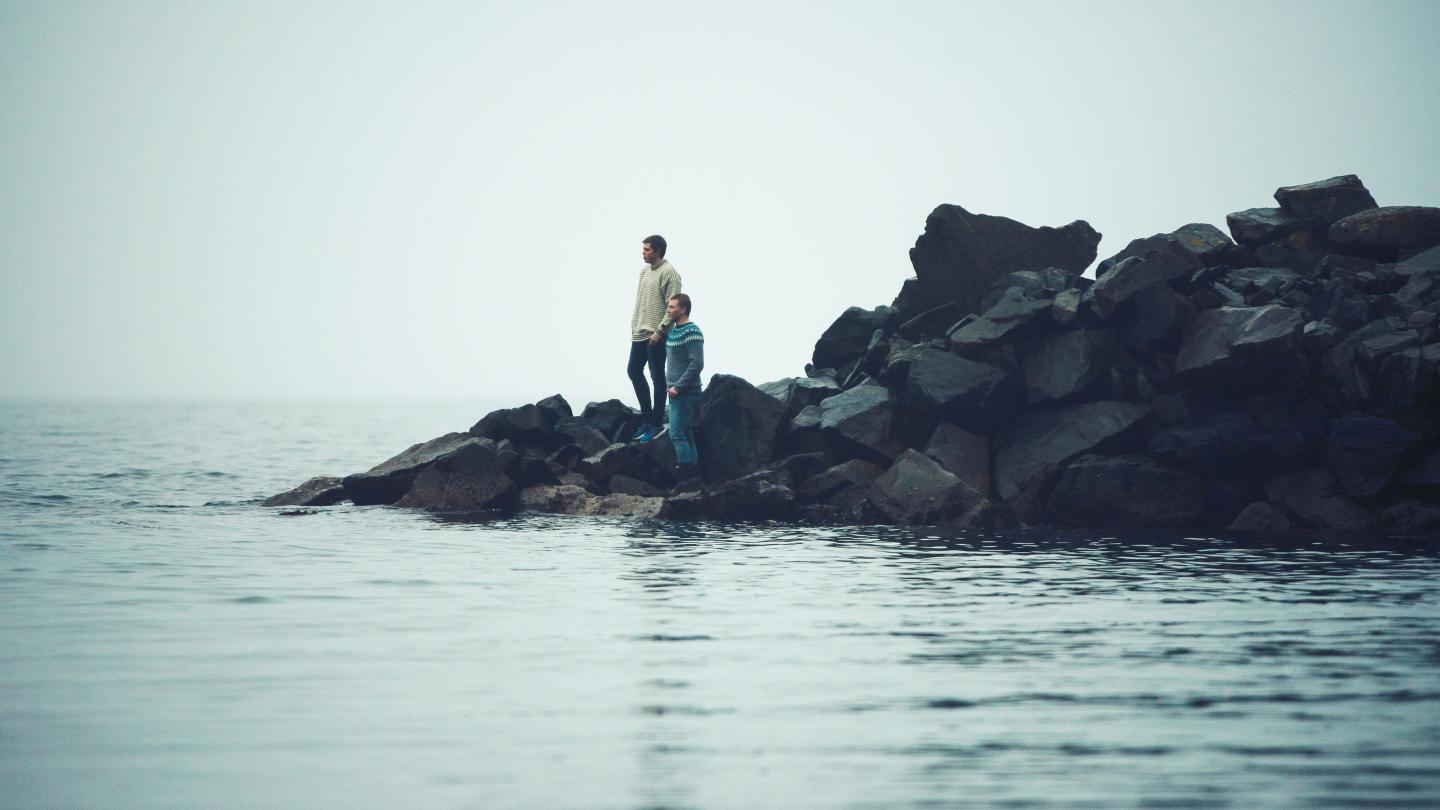 A couple standing on some rocks in the ocean