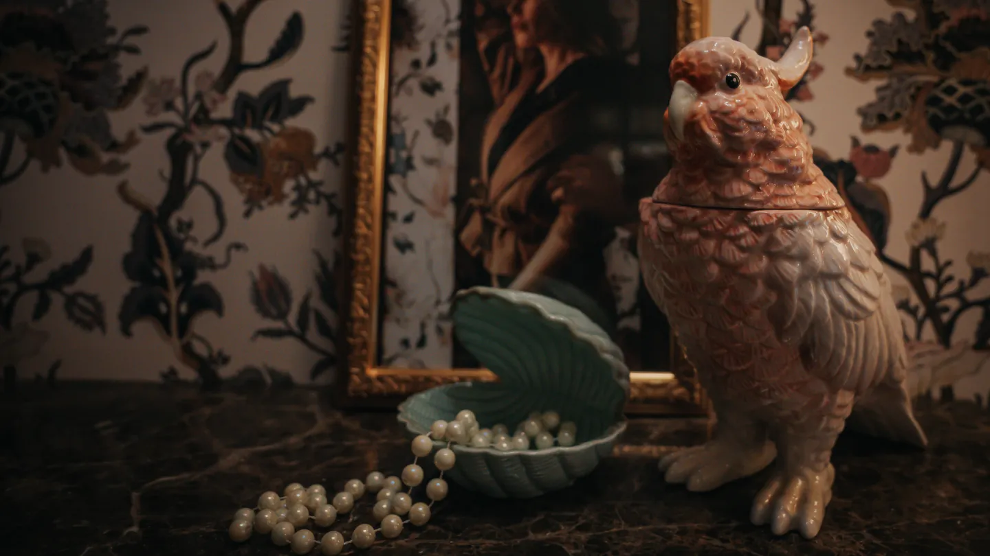 A detail from Charmante Skostredet Hôtel. A figurine of a dove, some pearls in a blue shell and a framed picture of a lady.