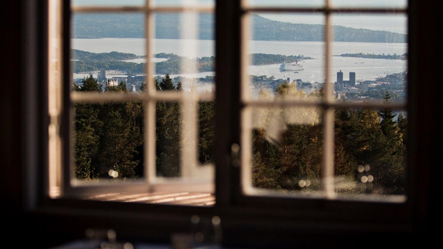 The view over Oslo seen through the window by the tables at Grefsenkollen restaurant