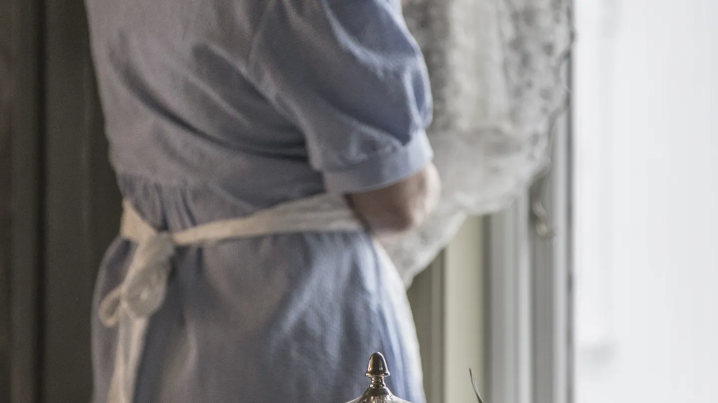 The hostess adjusting the curtains at Nevlunghavn Gjestgiveri
