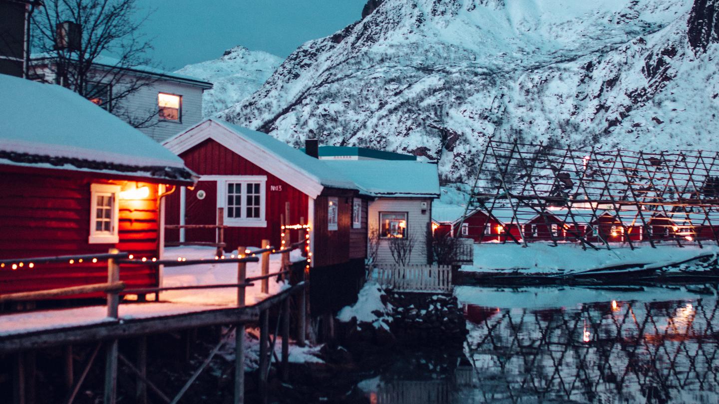 The exterior of Svinøya Rorbuer in front of snow covered mountains