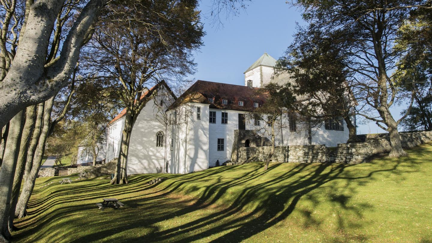 An exterior shot of Utstein Kloster Hotel with trees and grass around